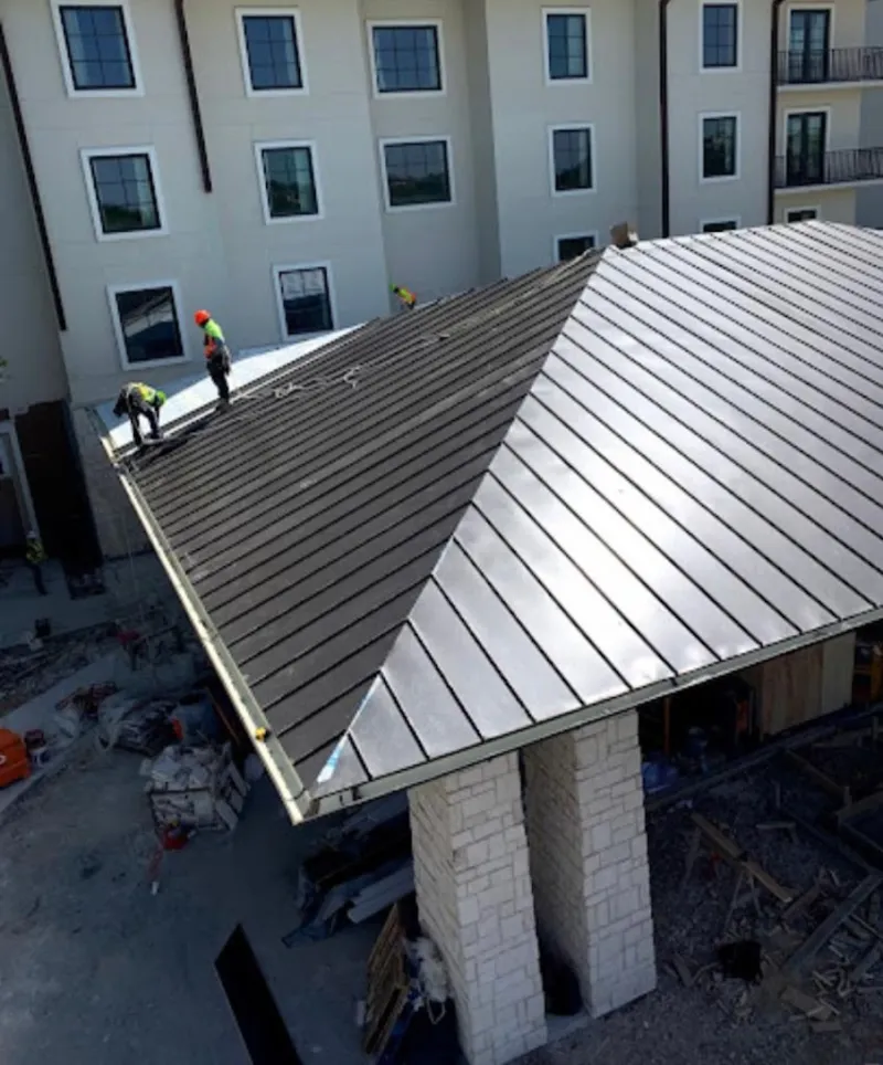 Crew installing standing seam metal roof panels on a commercial project in Seven Corners